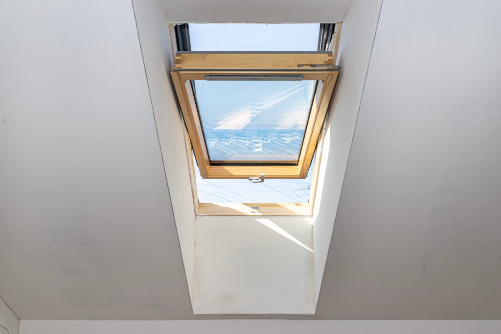 Grenier avec fenêtres de toit en état de gros œuvre fini, murs recouverts de plâtre.