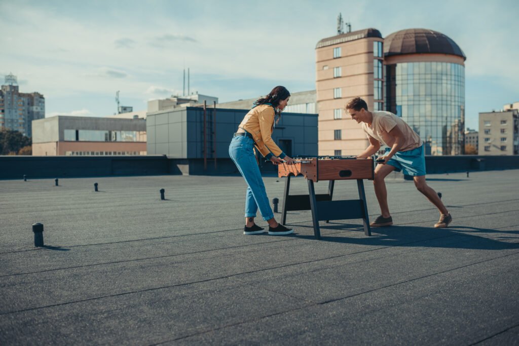 Couple enthousiaste jouant au baby-foot sur un toit.