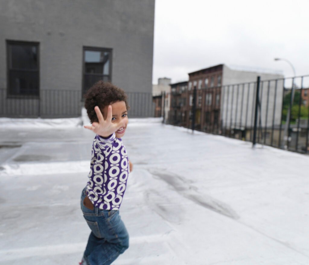 Jeune fille courant sur une terrasse de toit, souriante.